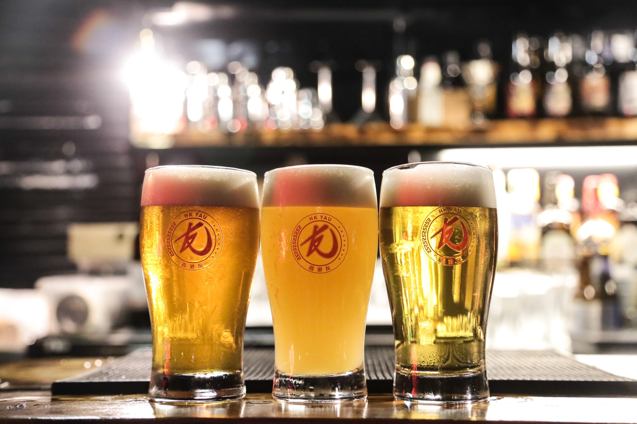 three pints of fresh draft beer with HK YAU logo printed on glass