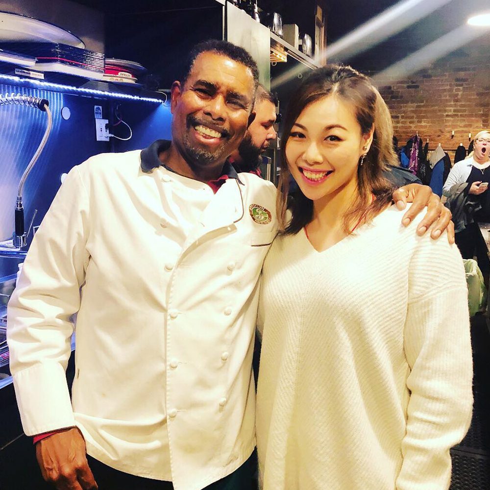 Photo of a black chef and an asian woman smiling at the camera is used as HK YAU social media post