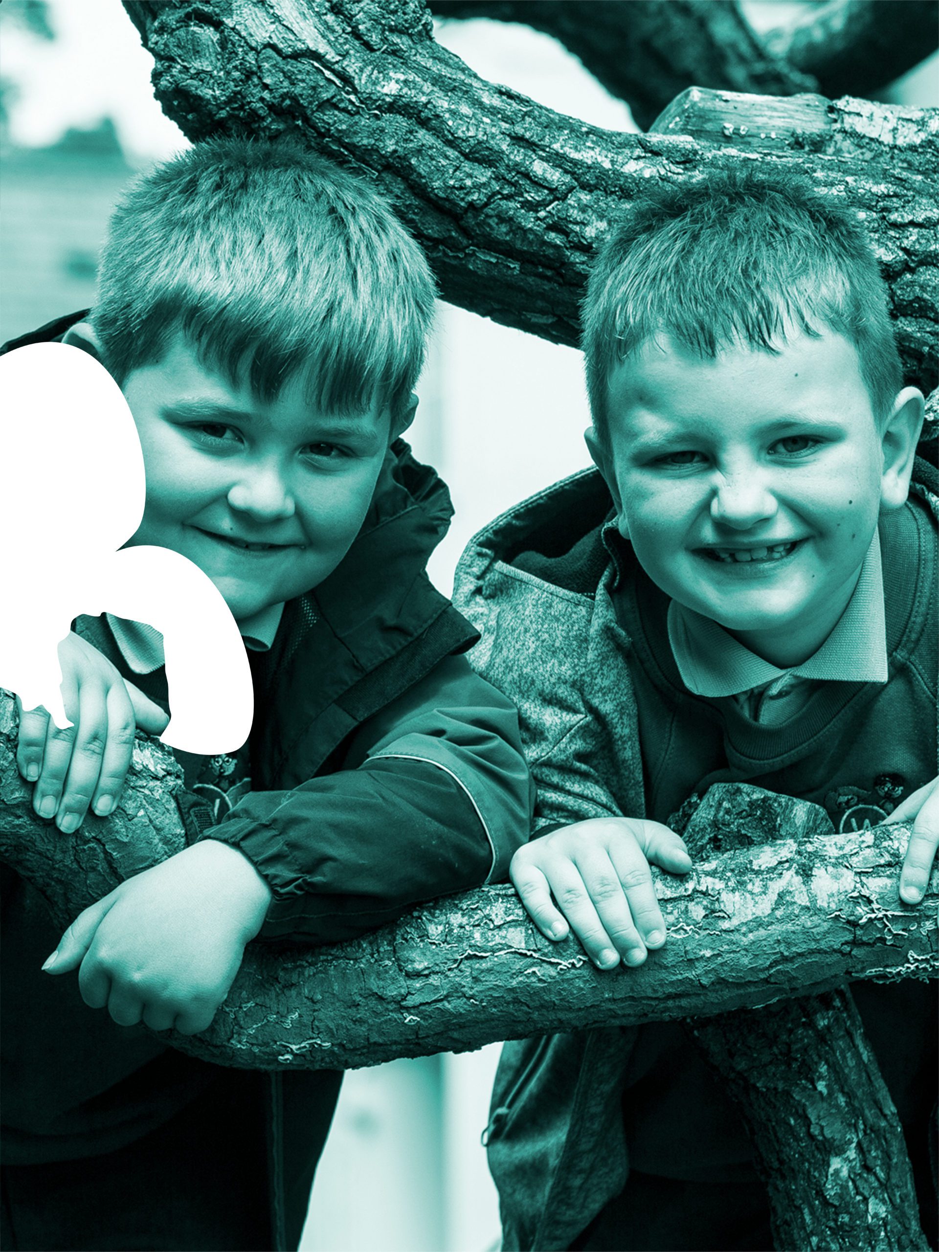 Two young boys smiling at the camera next to the tree with green filter