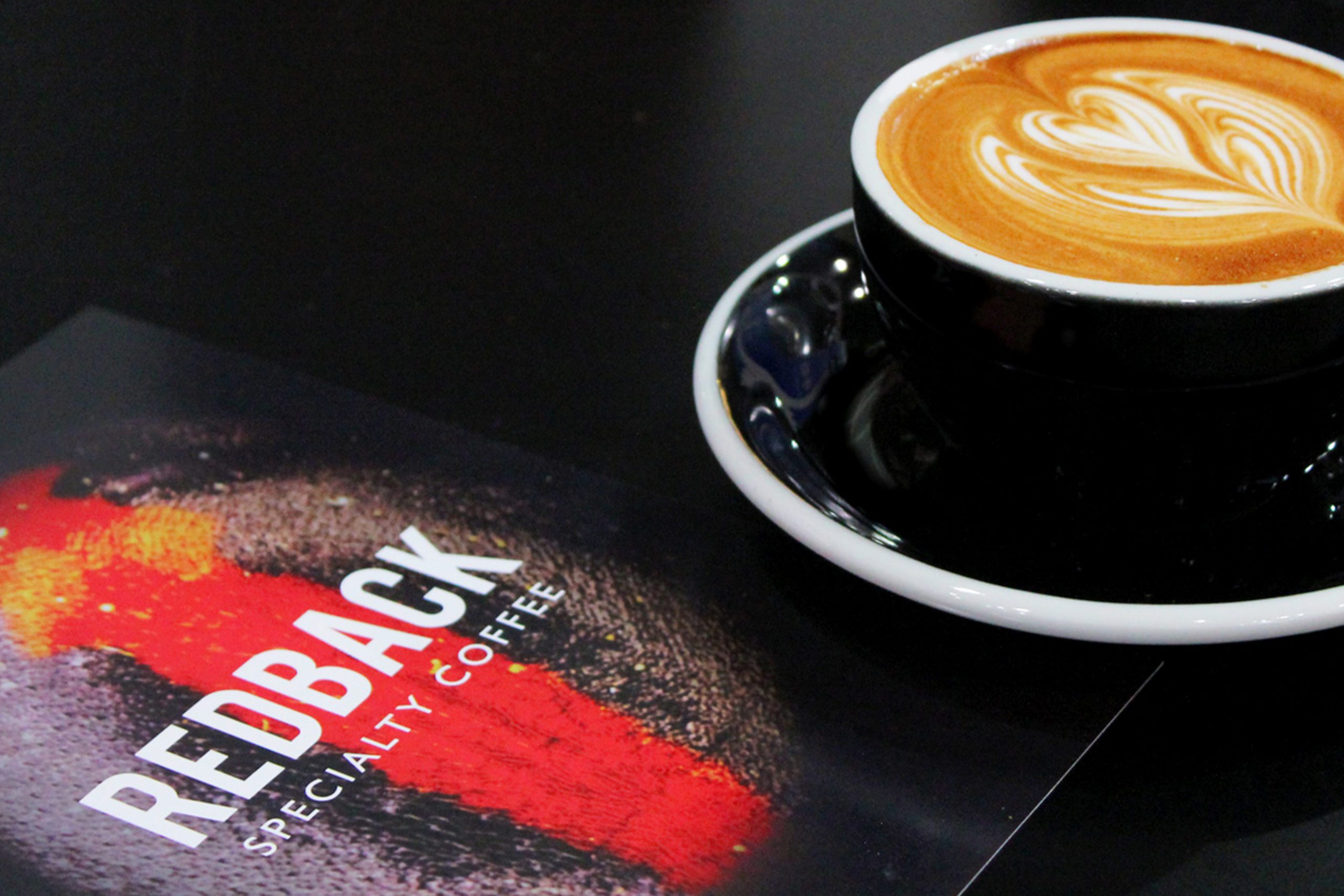 Redback Coffee branding logo next to a coffee