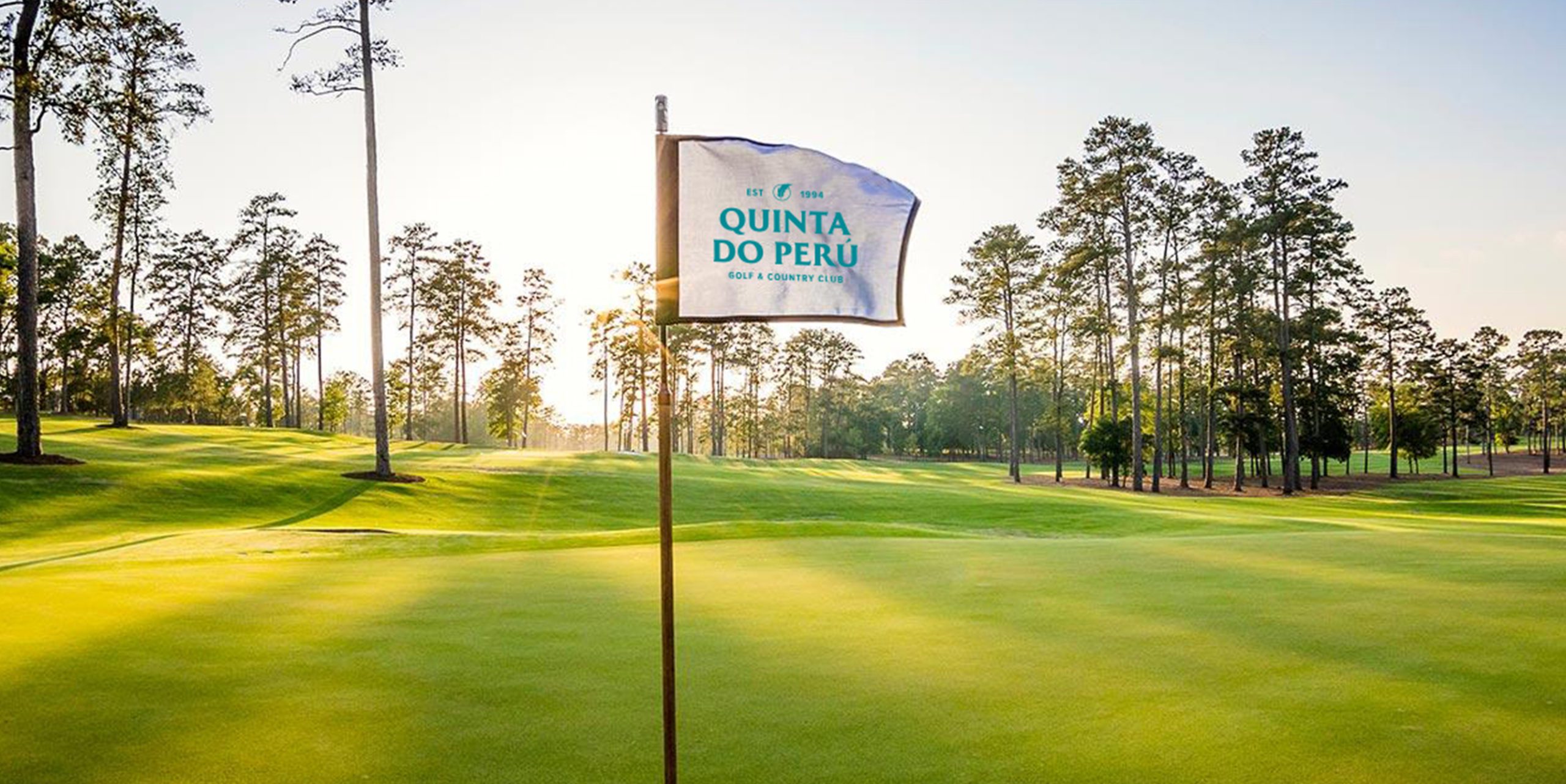 QDP Quinta Do Peru Golf & Country Club logo flag in green golf course in a sunny windy day