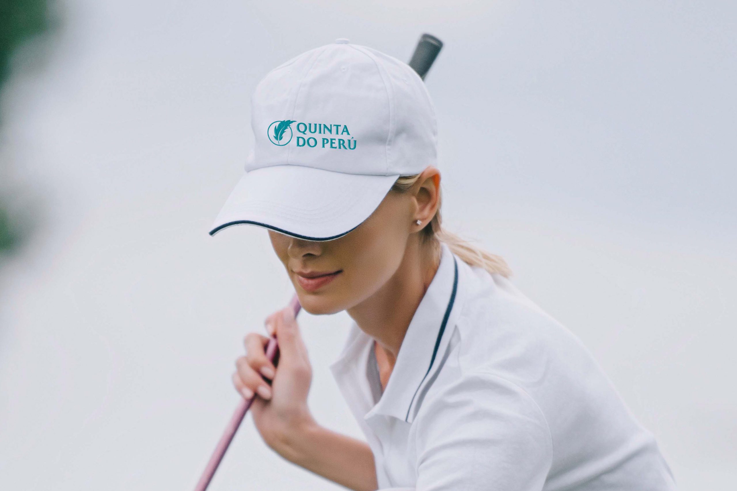 QDP Quinta Do Peru Golf & Country Club turquoise logo printed on golf cap worn by a female golfer