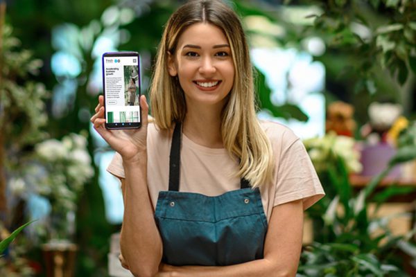 Pretty florist showing Fresh Accounting website page on her phone to the camera
