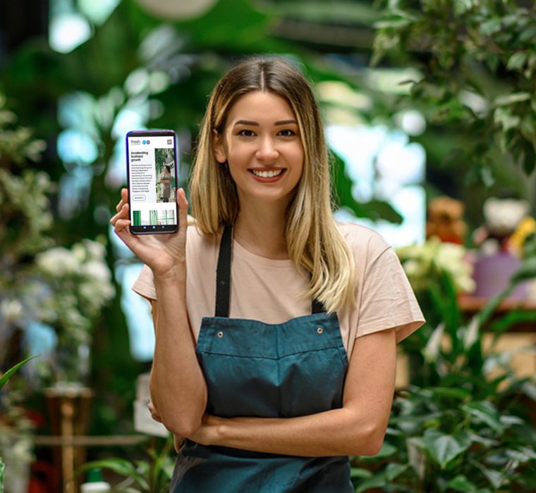Pretty florist showing Fresh Accounting website page on her phone to the camera