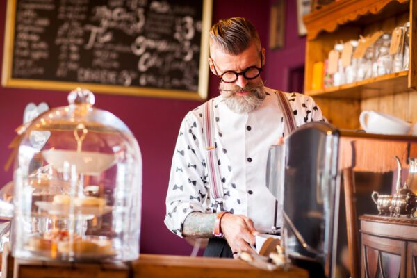 senior man using coffee machine in newly branded startup business